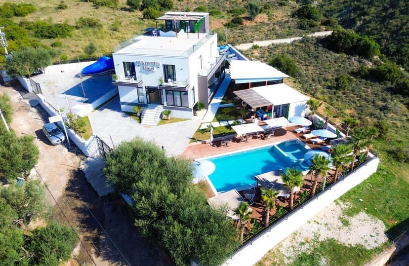 Sea Queen Hotel in Vlore with modern white building, outdoor pool, and surrounding green hills.