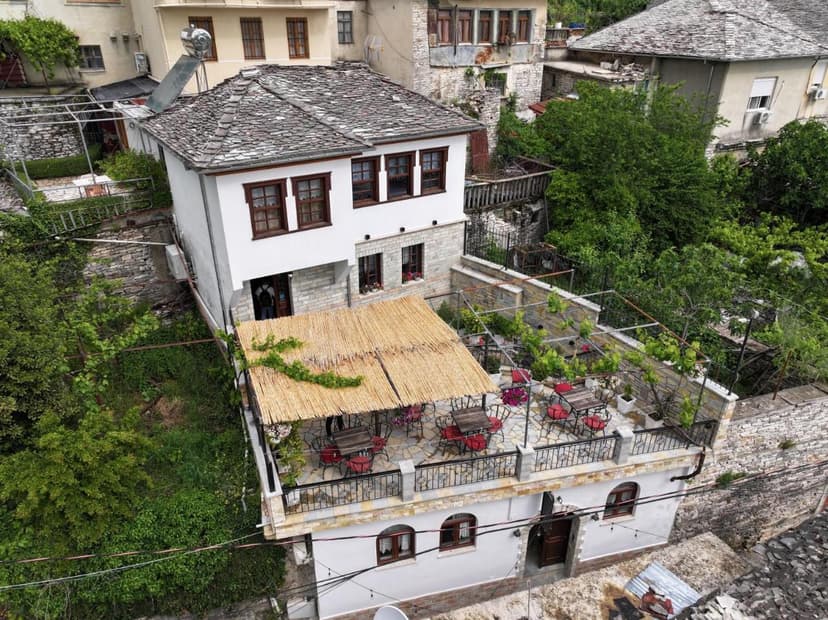 Hotel Pashai Gjirokaster with stone roof and outdoor dining terrace surrounded by greenery.