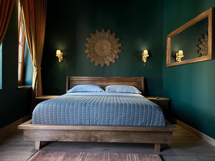Bedroom in Fole Guest House Pogradec with dark green walls and wooden bed frame.