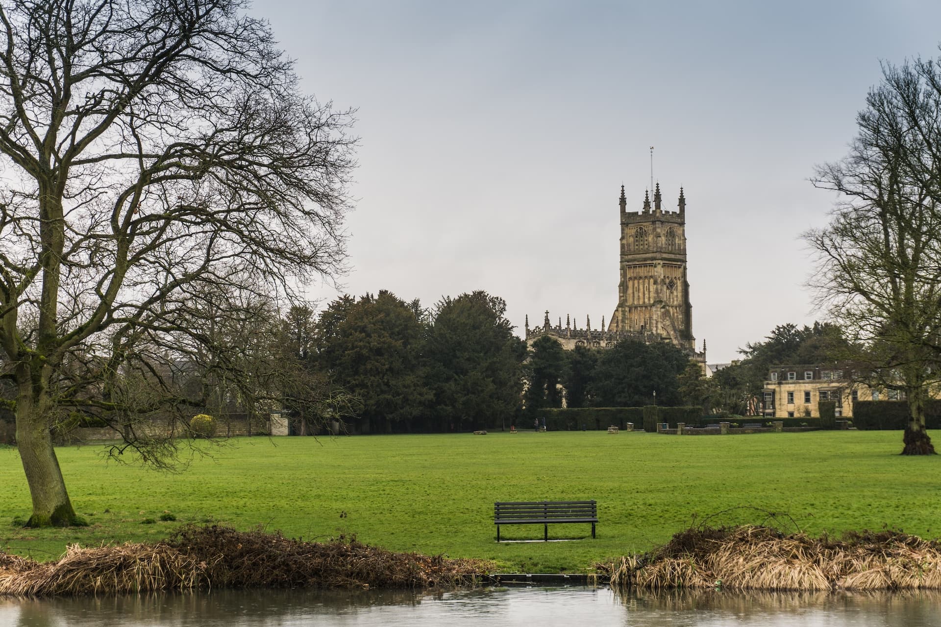 Cirencester Abbey Grounds with large church tower and bare trees in winter.