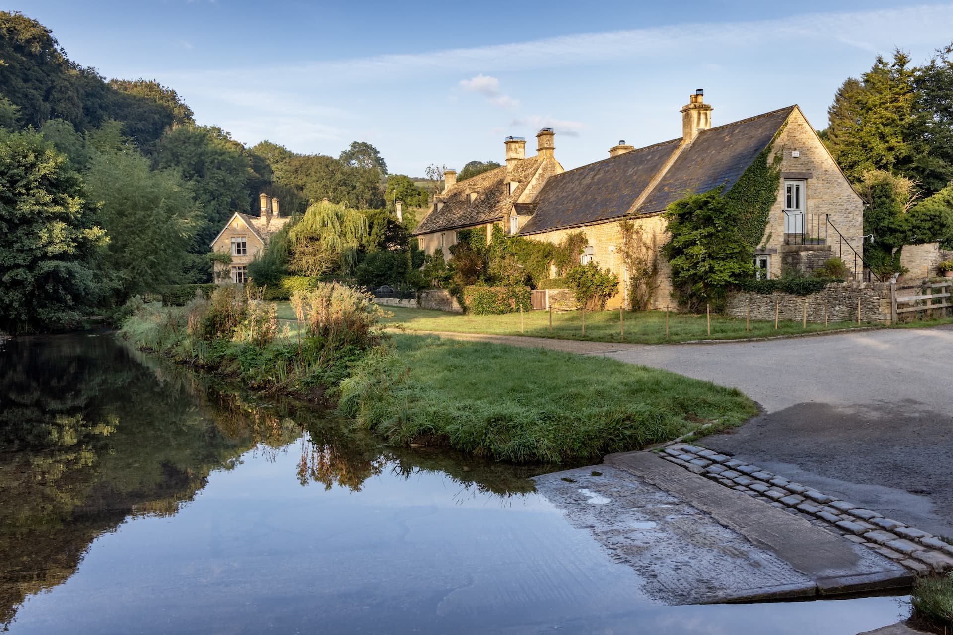 Stone cottages beside a river with a ford crossing in Upper Slaughter, Cotswolds.