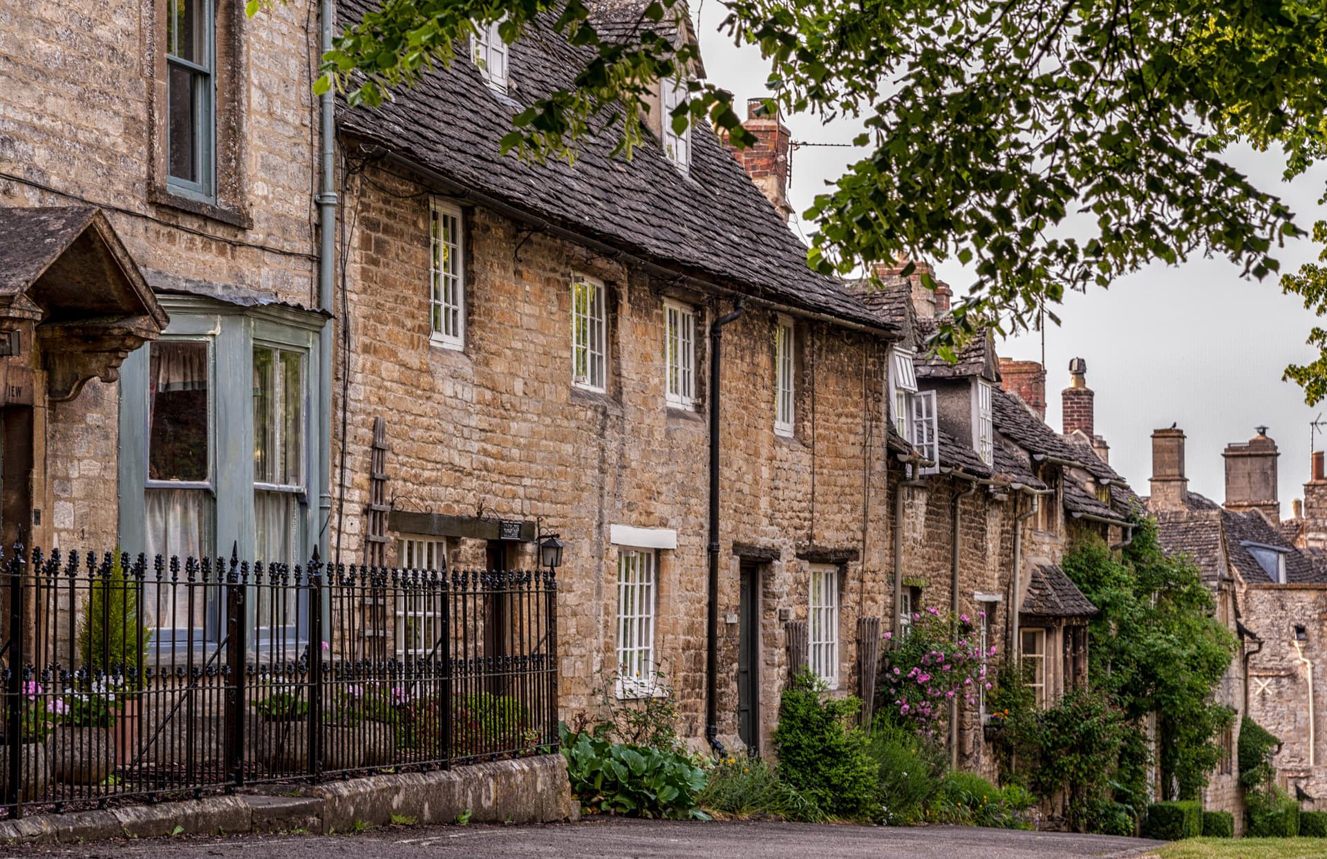 Stone cottages with slate roofs and lush greenery in the Cotswolds.