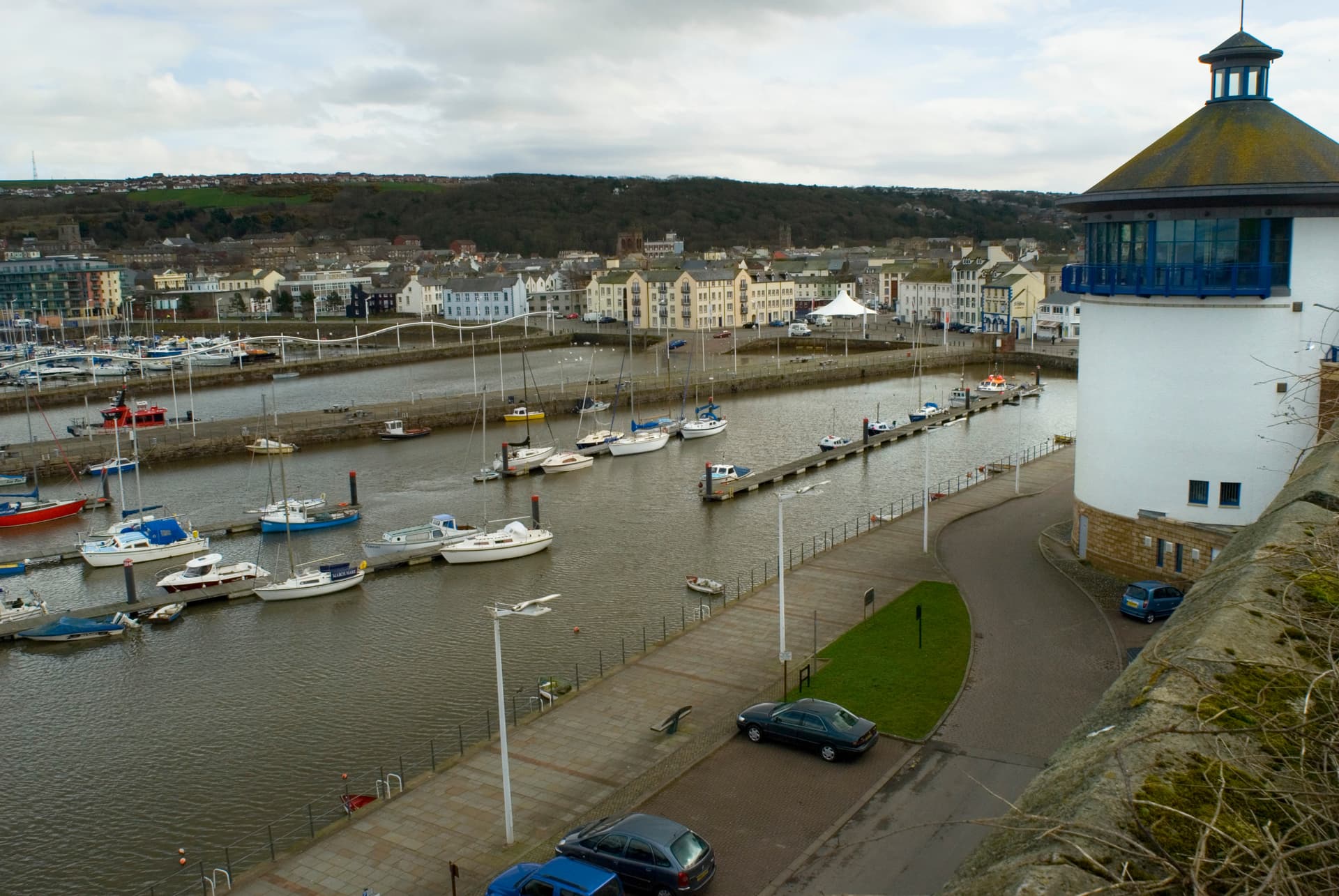 Boats moored in Whitehaven Harbour with town and wooded hillside in the background