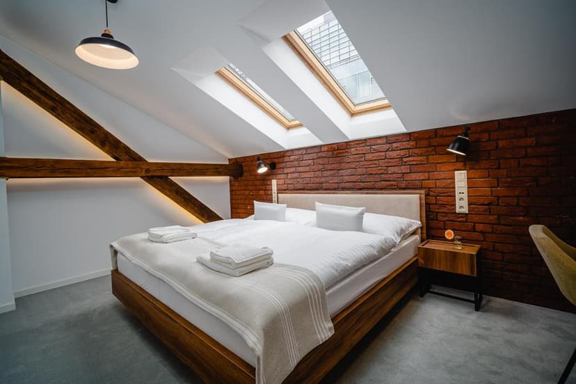 Attic hotel room with wood beams, exposed brick, and skylights in Garni-Hotel DOCK Bratislava