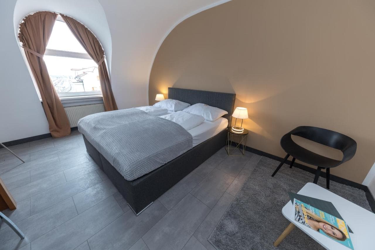 Hotel Atrigon room with a double bed, arched window with brown curtains, and modern furniture.