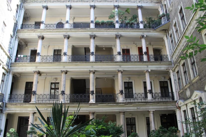 Courtyard of Omega Guesthouse Budapest with three tiers of balconies supported by columns.