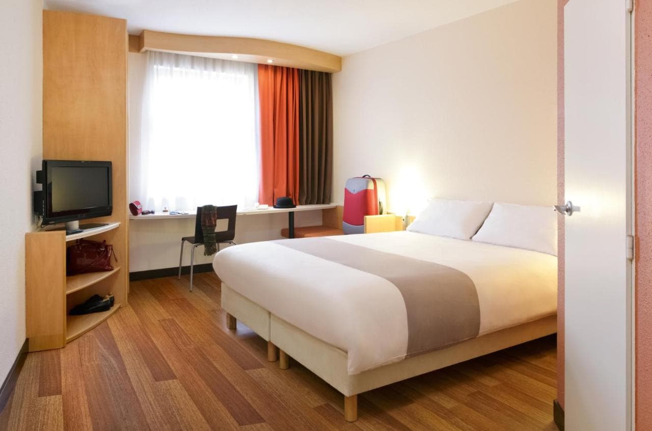 Ibis hotel room in Bratislava Centrum with wood floor, window, and bed.