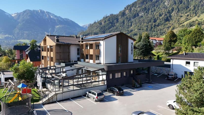 Hotel Hubertus building with parking lot, playground, and forested mountains in background