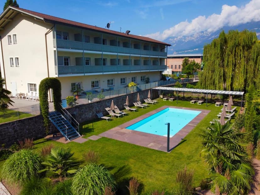 Hotel Turmwirt exterior with outdoor swimming pool, lounge chairs, and mountain backdrop