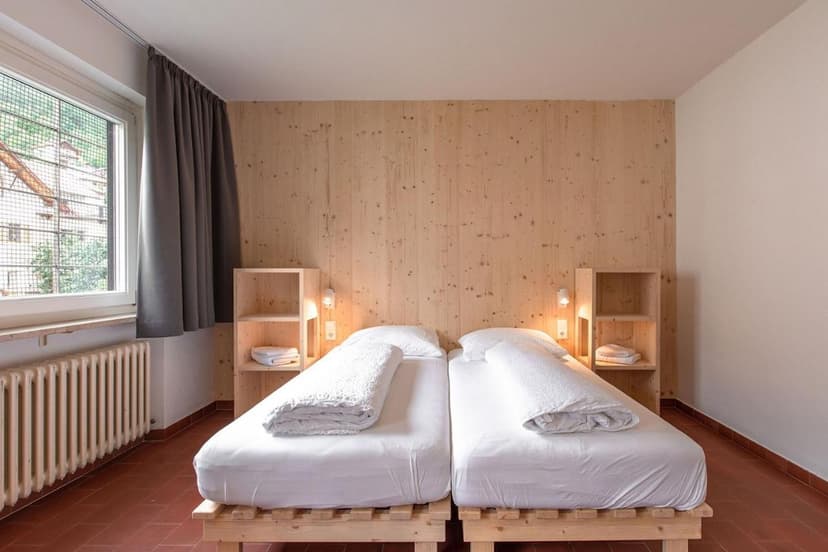 Twin beds with white duvets in a room with wood paneling and terracotta floor tiles