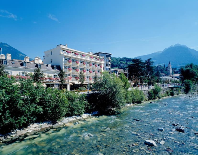 Hotel Aurora building next to a flowing river with mountains in the background