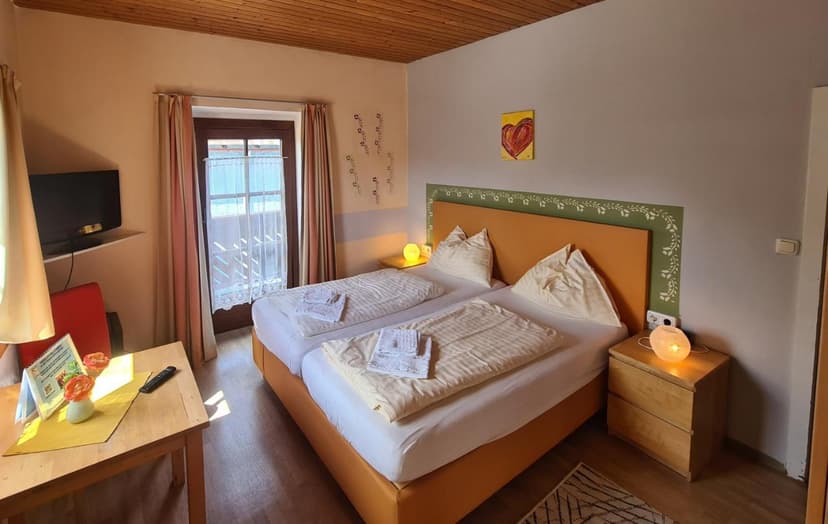 Twin beds with white linens in a room with wood ceiling and balcony door, Pension Göschlberger.