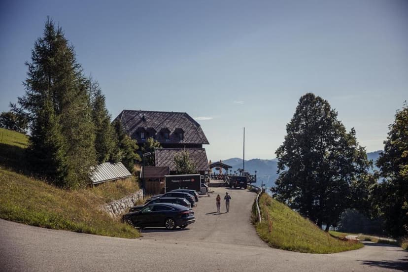 Gmundnerberghaus building with parking lot, people walking, and mountain view.
