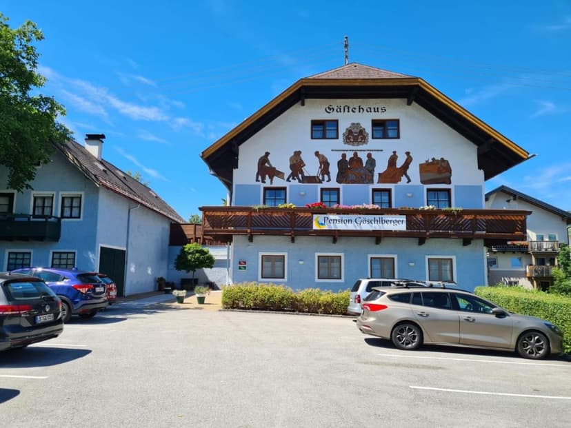 Gästehaus Pension Göschlberger with mural, parked cars, and blue sky.
