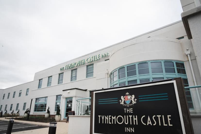 The Tynemouth Castle Inn building exterior with a large black and white sign in the foreground.