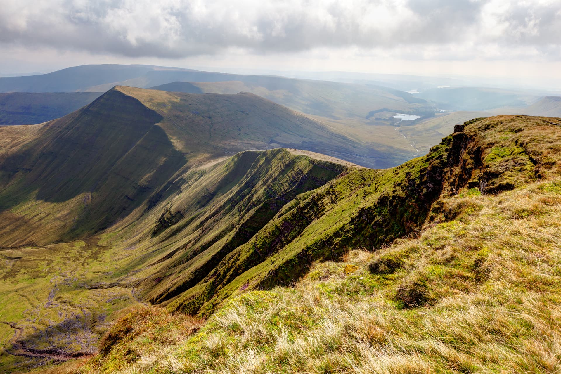 Rolling green and brown hillsides with steep grassy slopes in Brecon Beacons National Park.