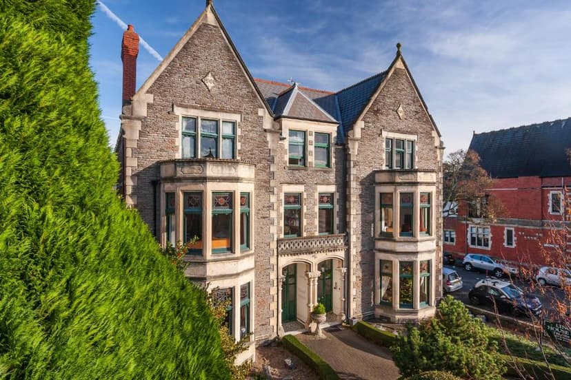 Stone Victorian-style building exterior, Lincoln House Private Hotel, with large green hedge.