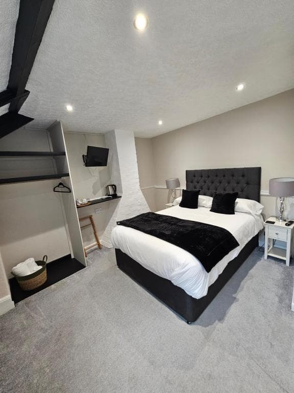 Bedroom with double bed, black headboard, white linens, and grey carpet in The Beacons Guest House.