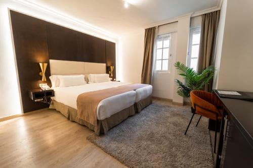 Hotel room with twin beds, modern dark wood headboard, and orange accent chair in Tenerife