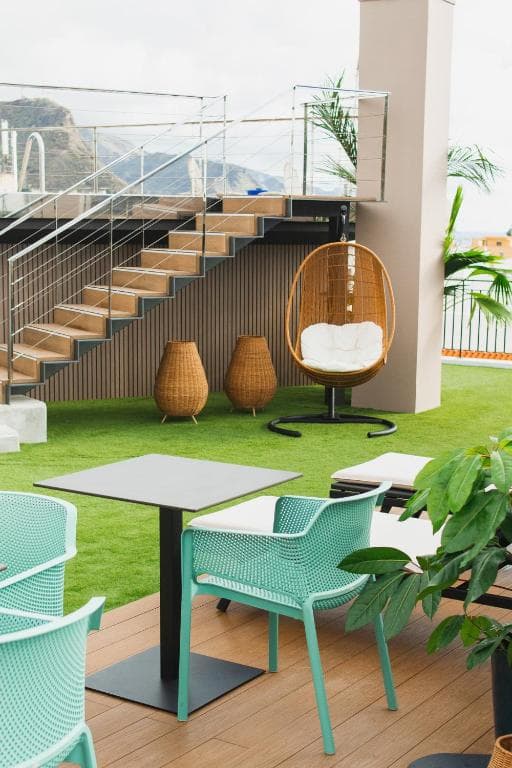 Outdoor terrace with artificial grass, modern seating, and stairs leading up, Hotel Taburiente S.C. Tenerife.