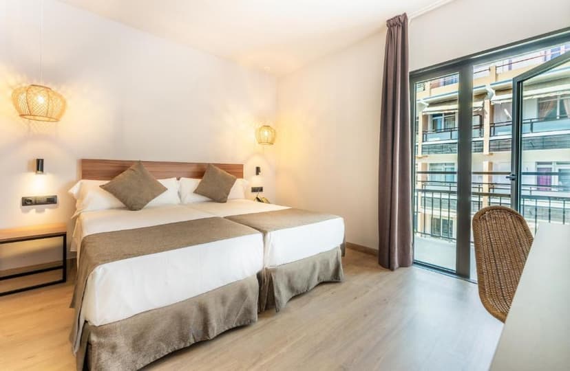 Twin beds with white linens and brown accents in a modern hotel room with balcony access.