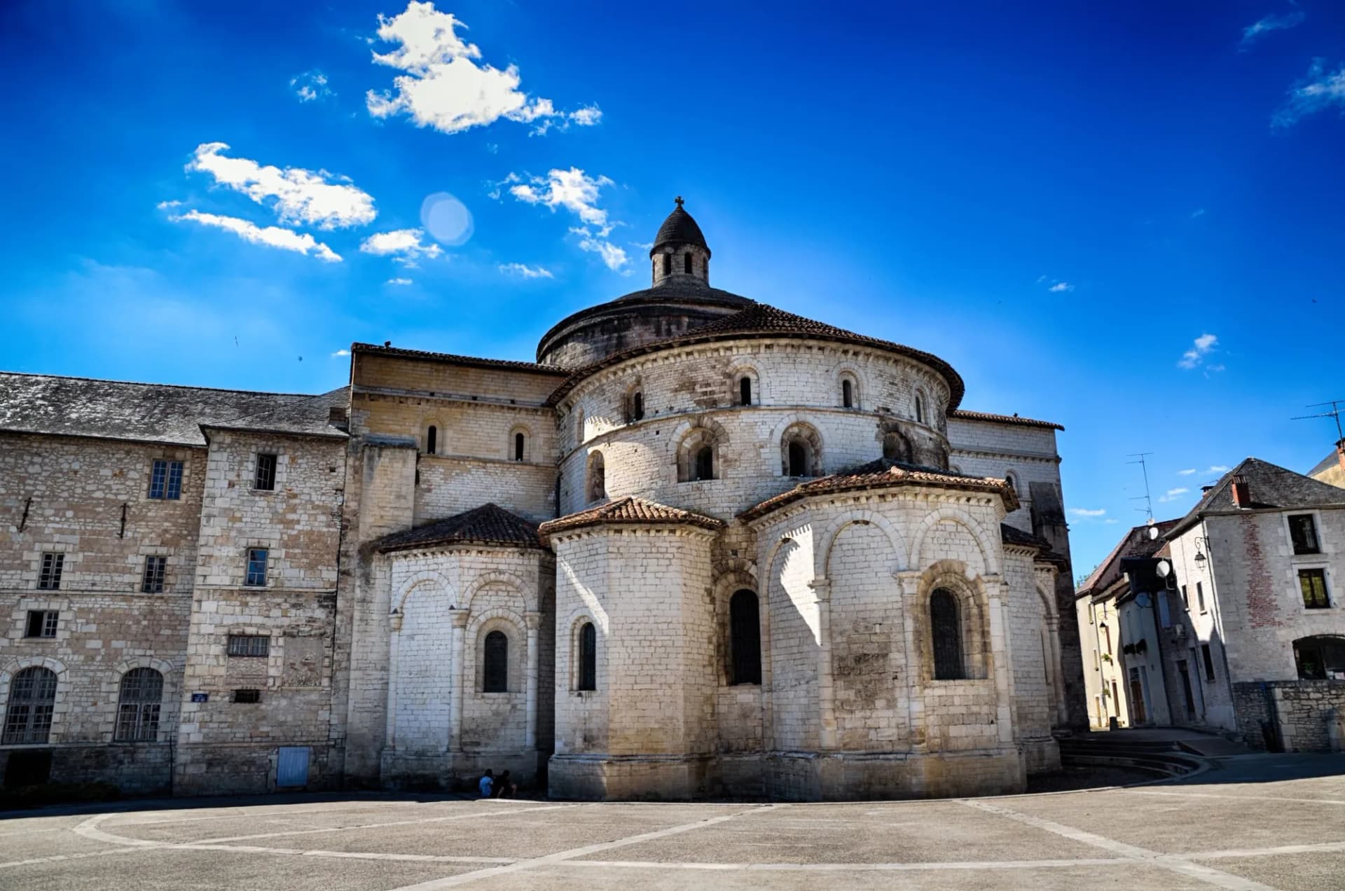 Romanesque church apse with stone facade under bright blue sky in Souillac.