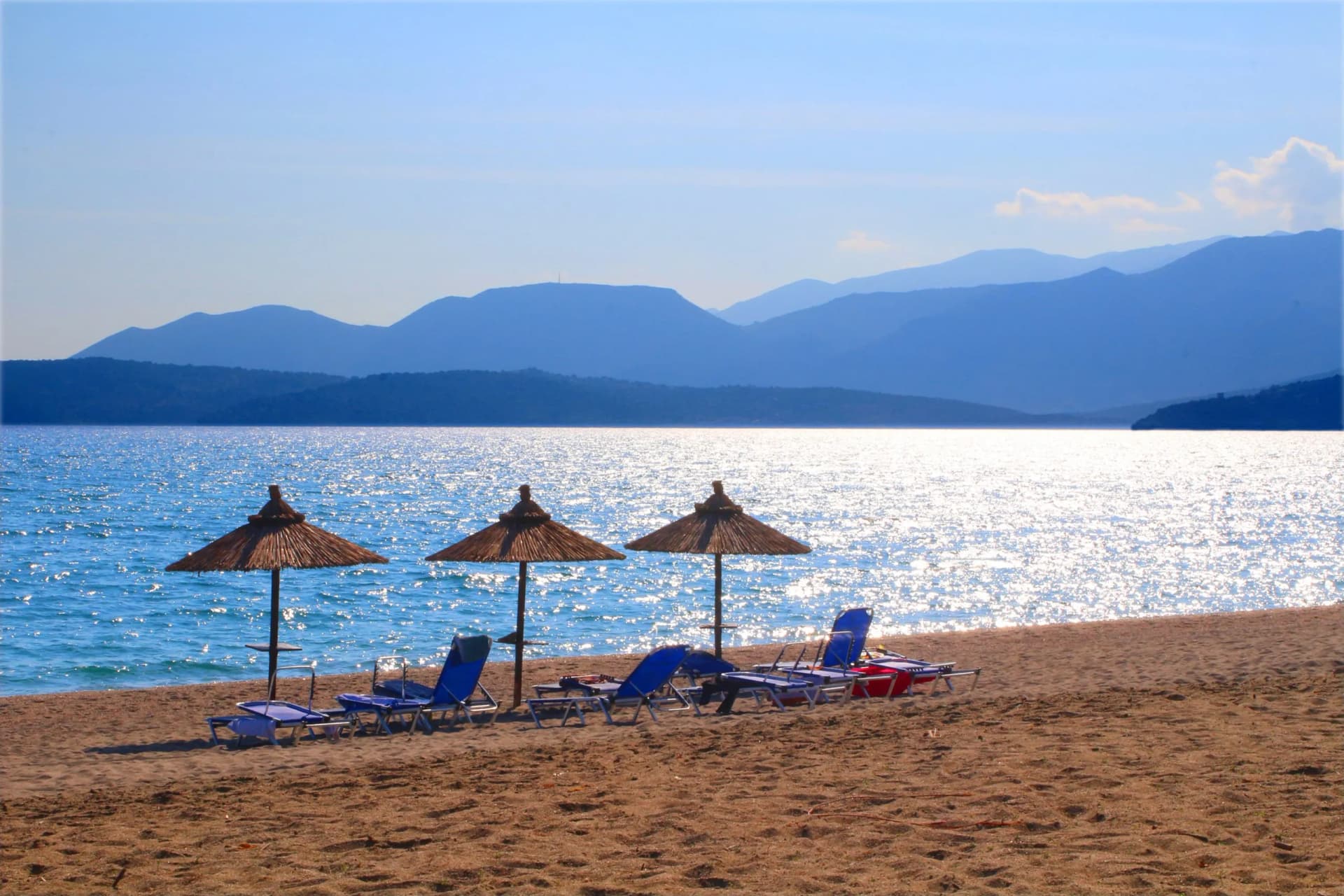 Parasols at the beach in front of the Peloponnesian mountains, Gythio bay, Greece