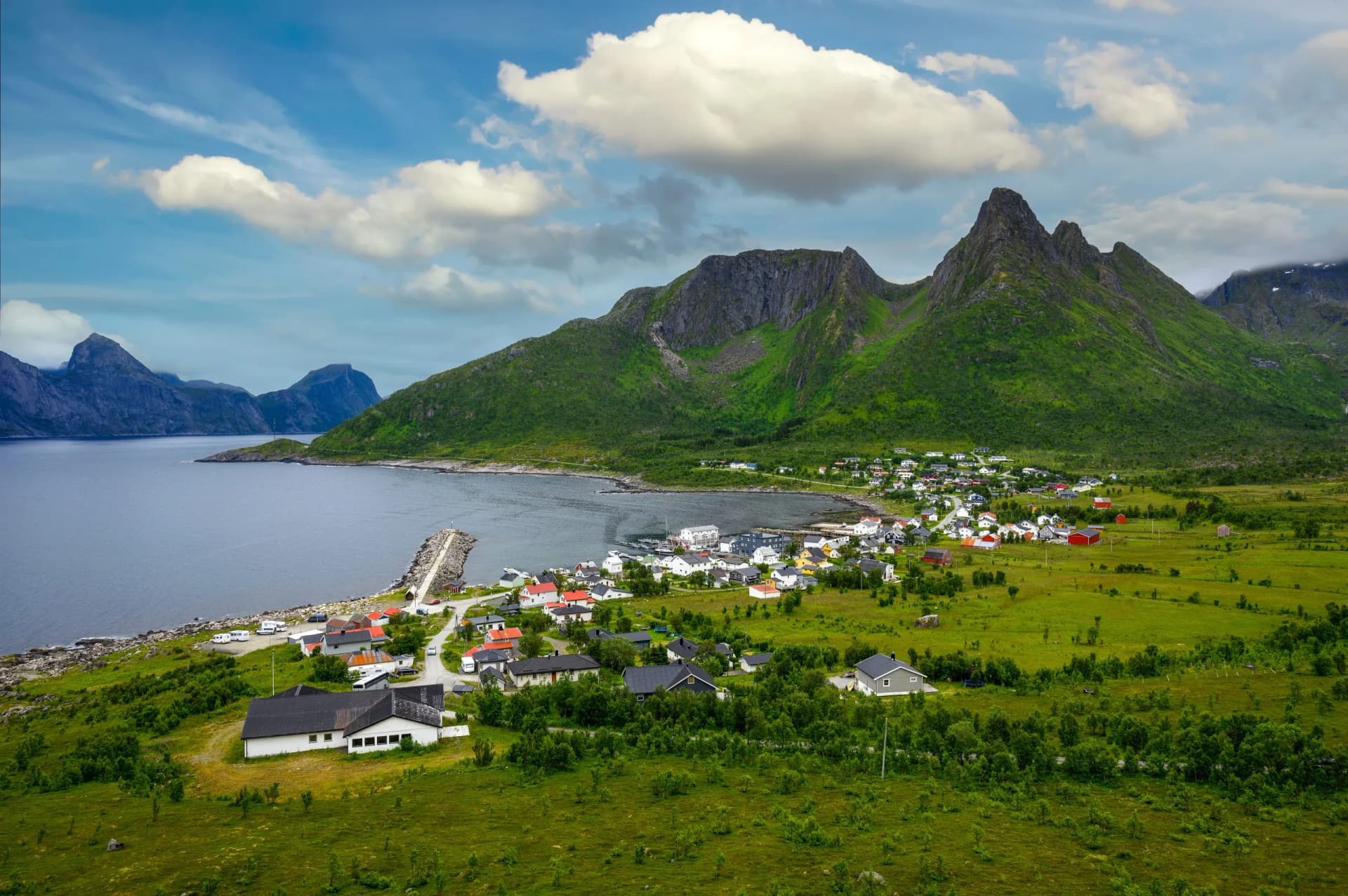 Aerial view of Mefjordvaer village on Senja Island, with majestic mountains and the serene Mefjorden fjord weaving a picturesque Norwegian backdrop.