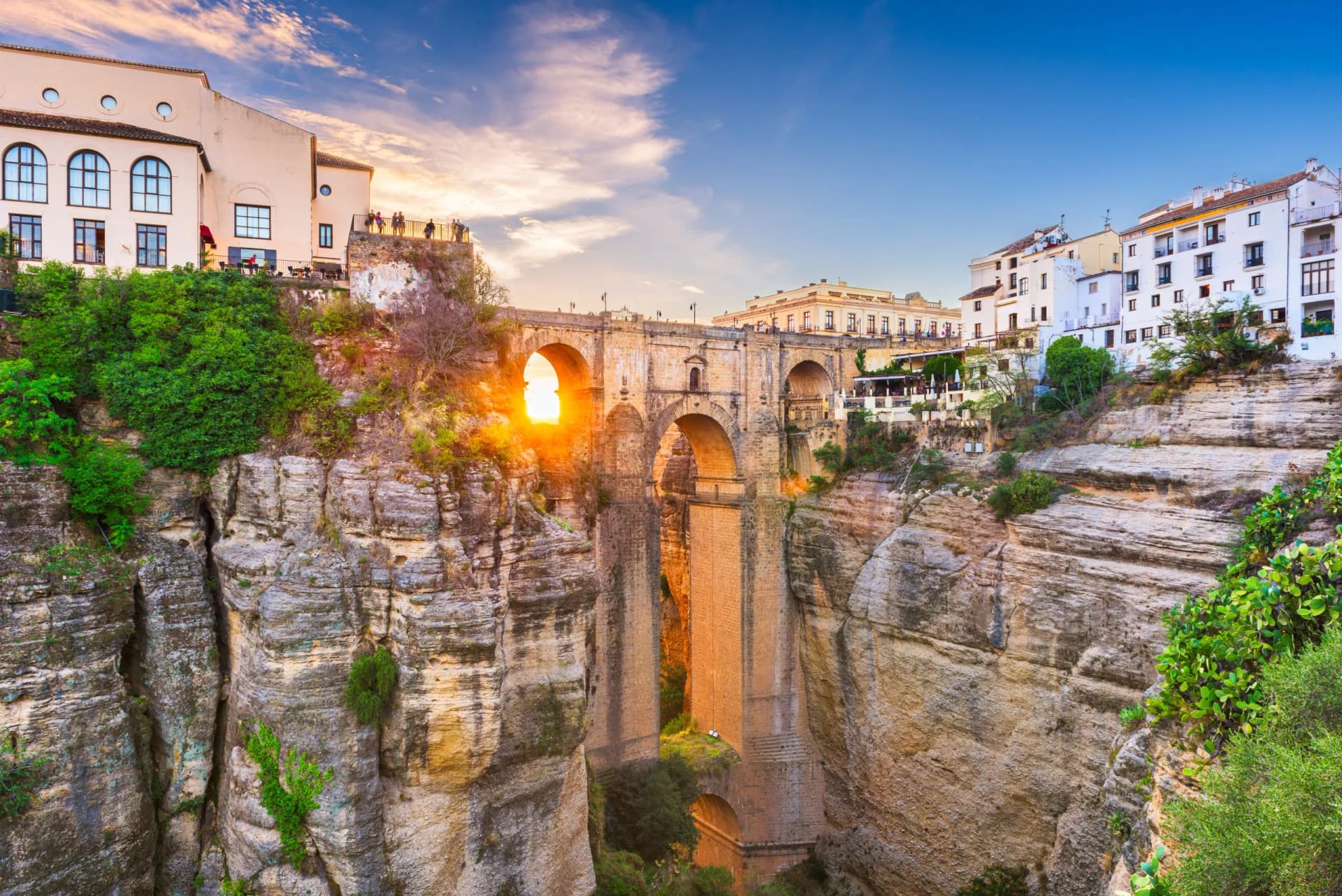 Puente Nuevo bridge over gorge with white buildings in Ronda, Spain at sunset