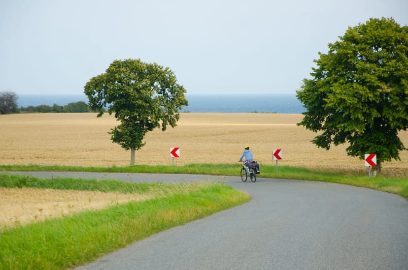 Lonely cycle tourist on the scenic countryside road in Denmark - island Mon.