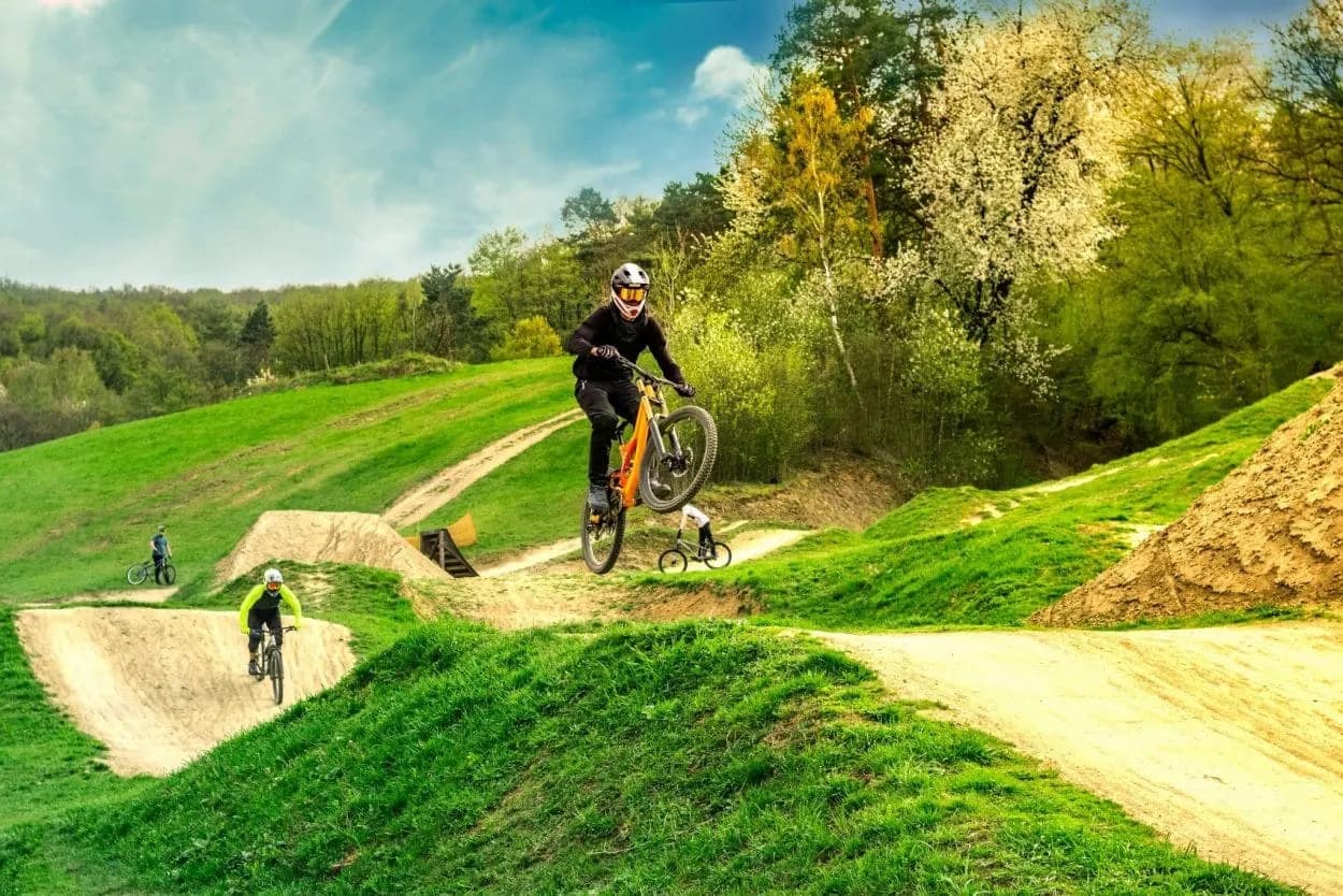 Mountain biker catching air on dirt jump trail at Kočevje trail center.