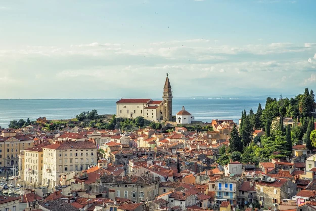 Town of Piran with St. George's Parish Church overlooking terracotta roofs and the Adriatic Sea.