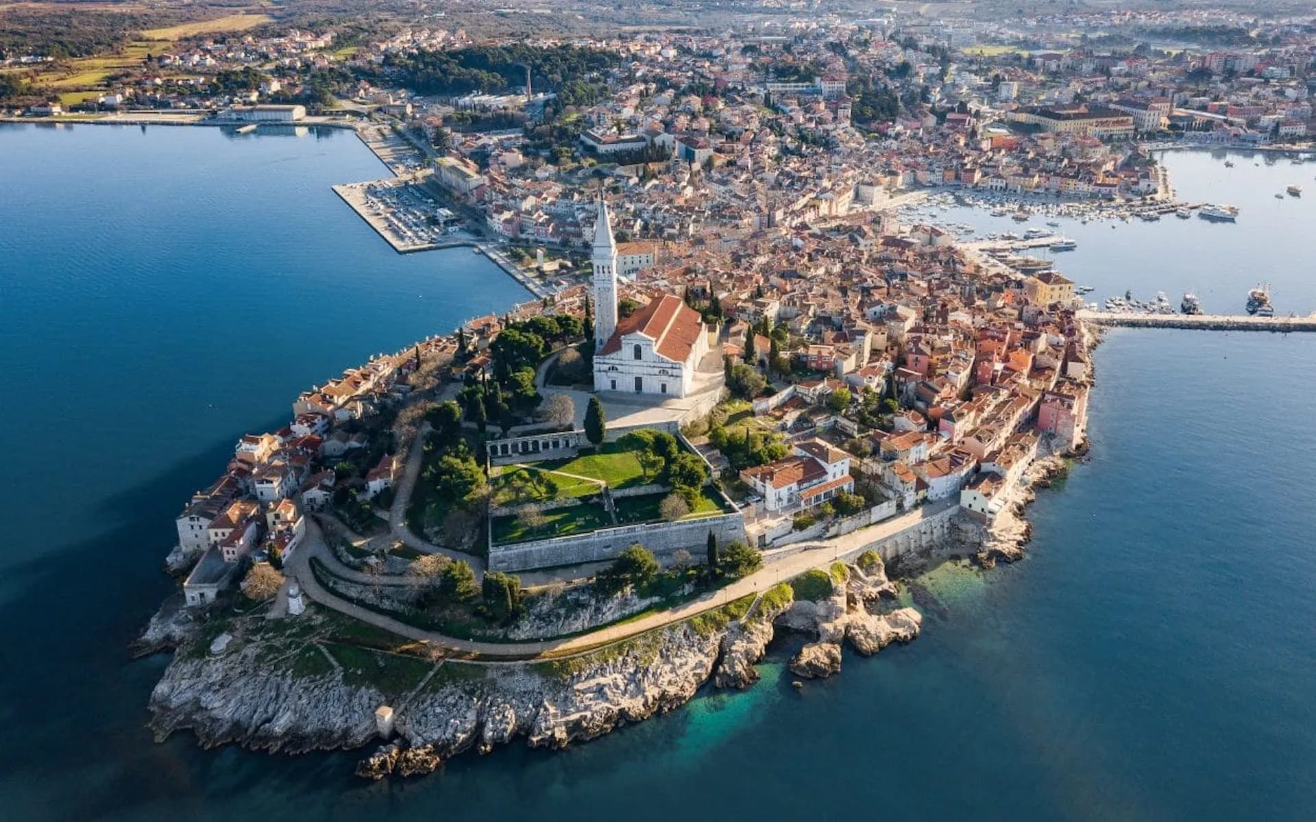 Aerial panorama of Rovinj peninsula town with St. Euphemia Church overlooking the Adriatic Sea.