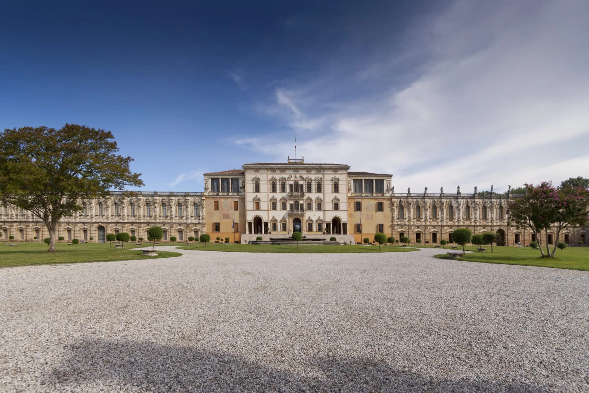 Villa Camerini with ornate facade, gravel drive, and green lawn under a blue sky.