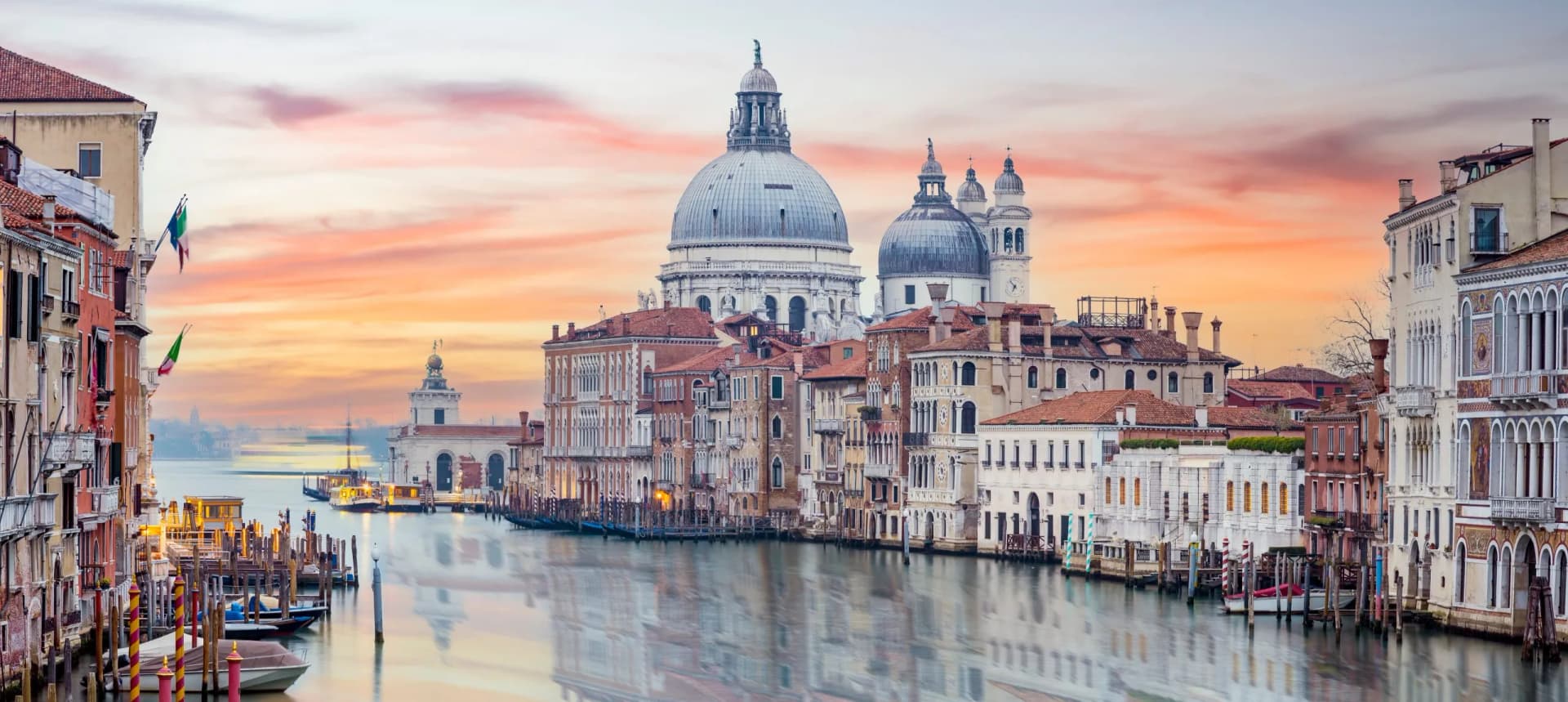 Grand Canal in Venice with Santa Maria della Salute at sunset, showing historic buildings and boats.