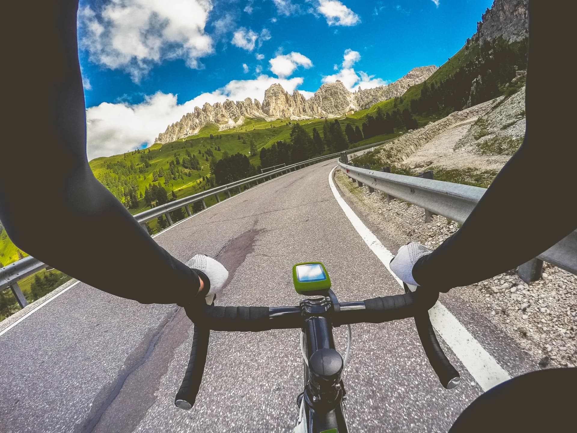 Cycling on mountain road toward jagged peaks in Corvara Dolomites, Italy.