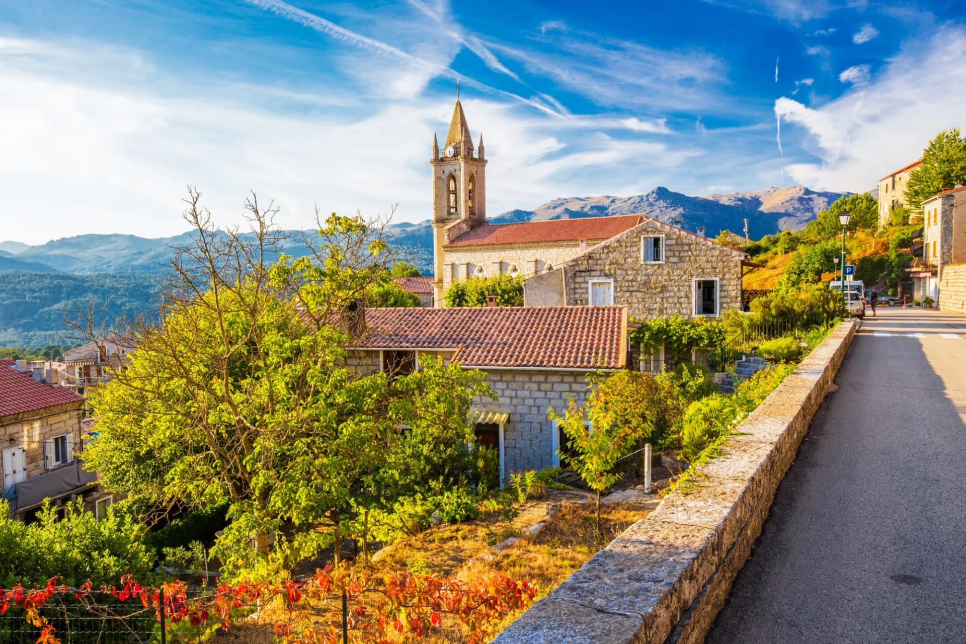 Stone village with church tower nestled in mountains under bright blue sky