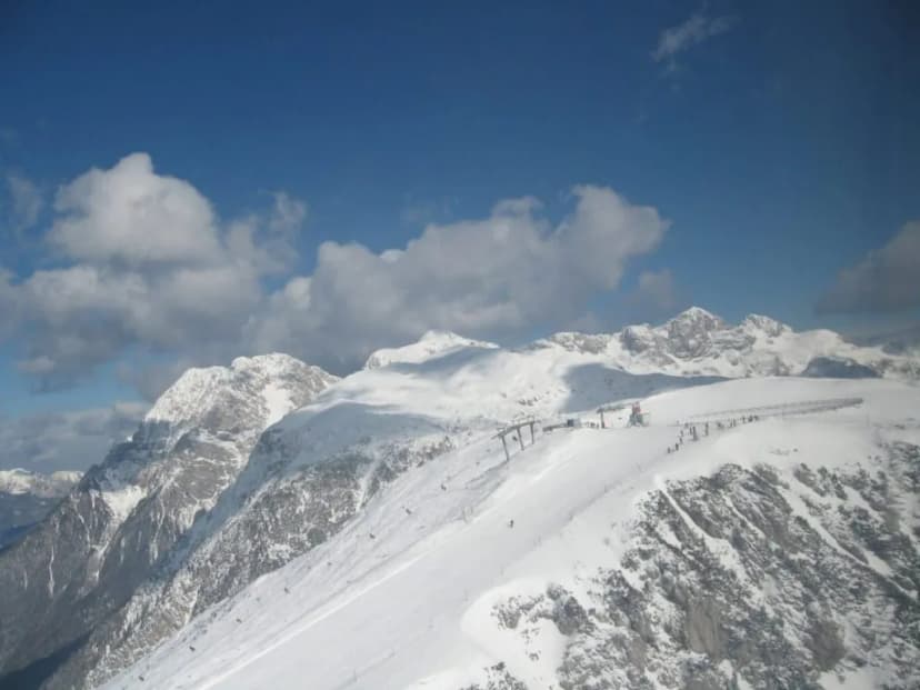 Ski resort with chairlift on snow-covered mountains under a blue sky with clouds