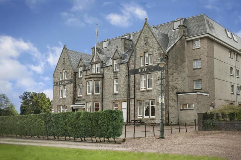 Alexandra Hotel building made of grey stone with a slate roof under a blue sky.