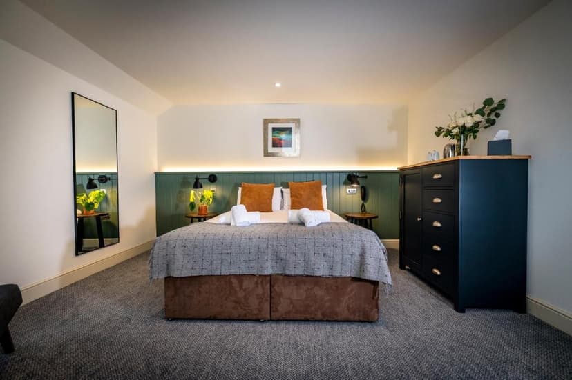 Bedroom in Loch Ness Inn with double bed, dark dresser, and full-length mirror.