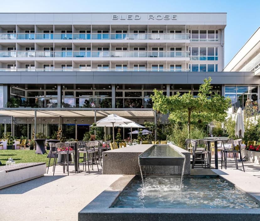 Hotel Bled Rose building exterior with outdoor patio seating and modern water feature