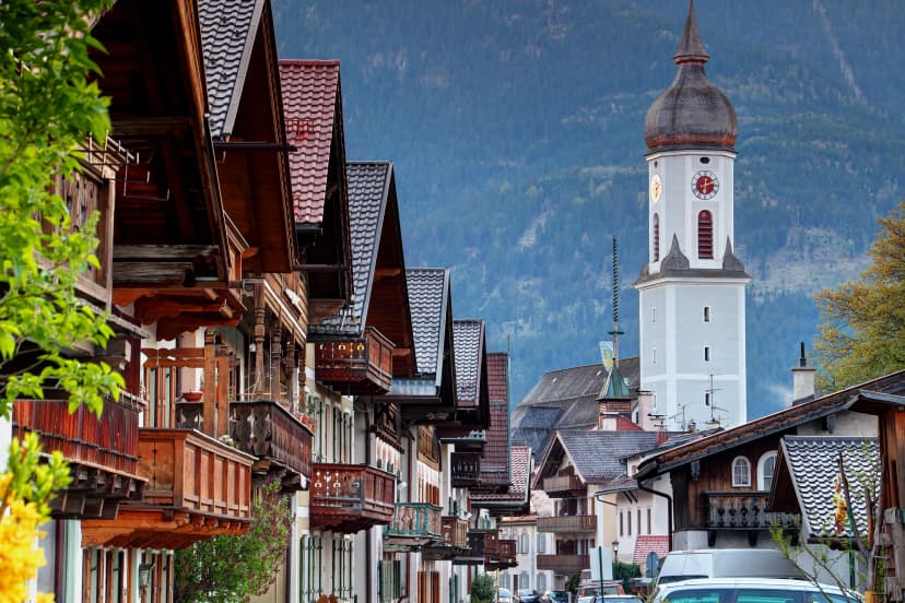 Traditional German houses with wooden balconies in historic center of Garmisch with Parish Church St. Martin and Wank mountain in background, Garmisch-Partenkirchen