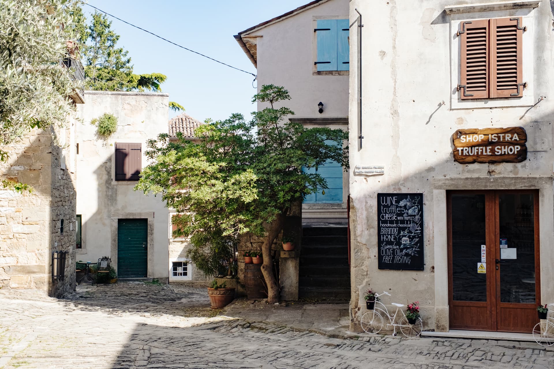 Truffle shop entrance on a sunlit cobblestone street in an old European town.