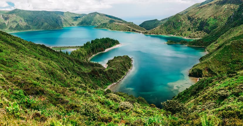 Lagoa do Fogo crater lake with turquoise water surrounded by steep, lush green volcanic slopes.