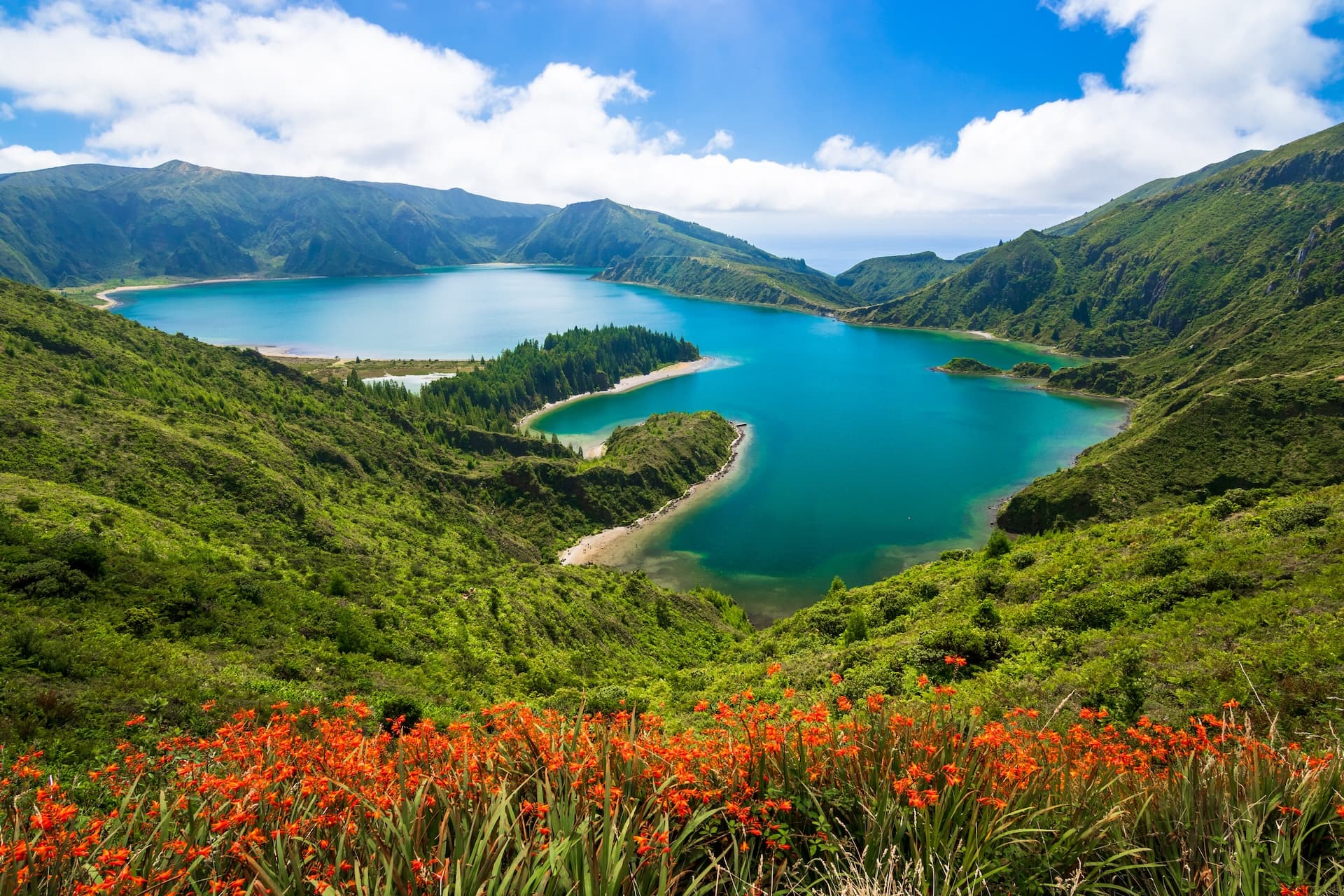 Lagoa do Fogo, Azores: Turquoise crater lake surrounded by lush green mountains and orange wildflowers.