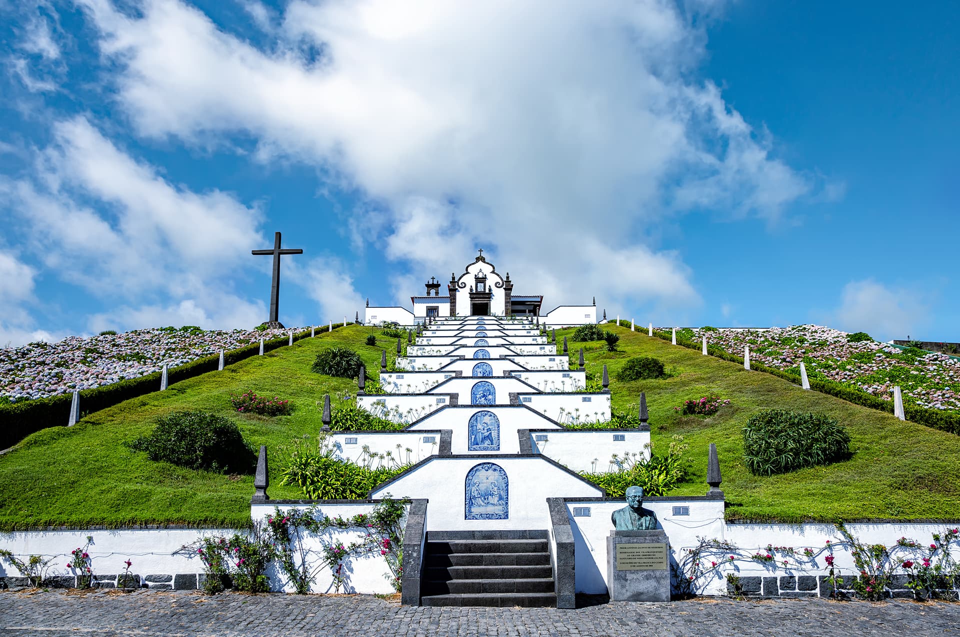 Santuario de Nossa Senhora da Paz with white steps, blue tiles, and a large cross under a blue sky.
