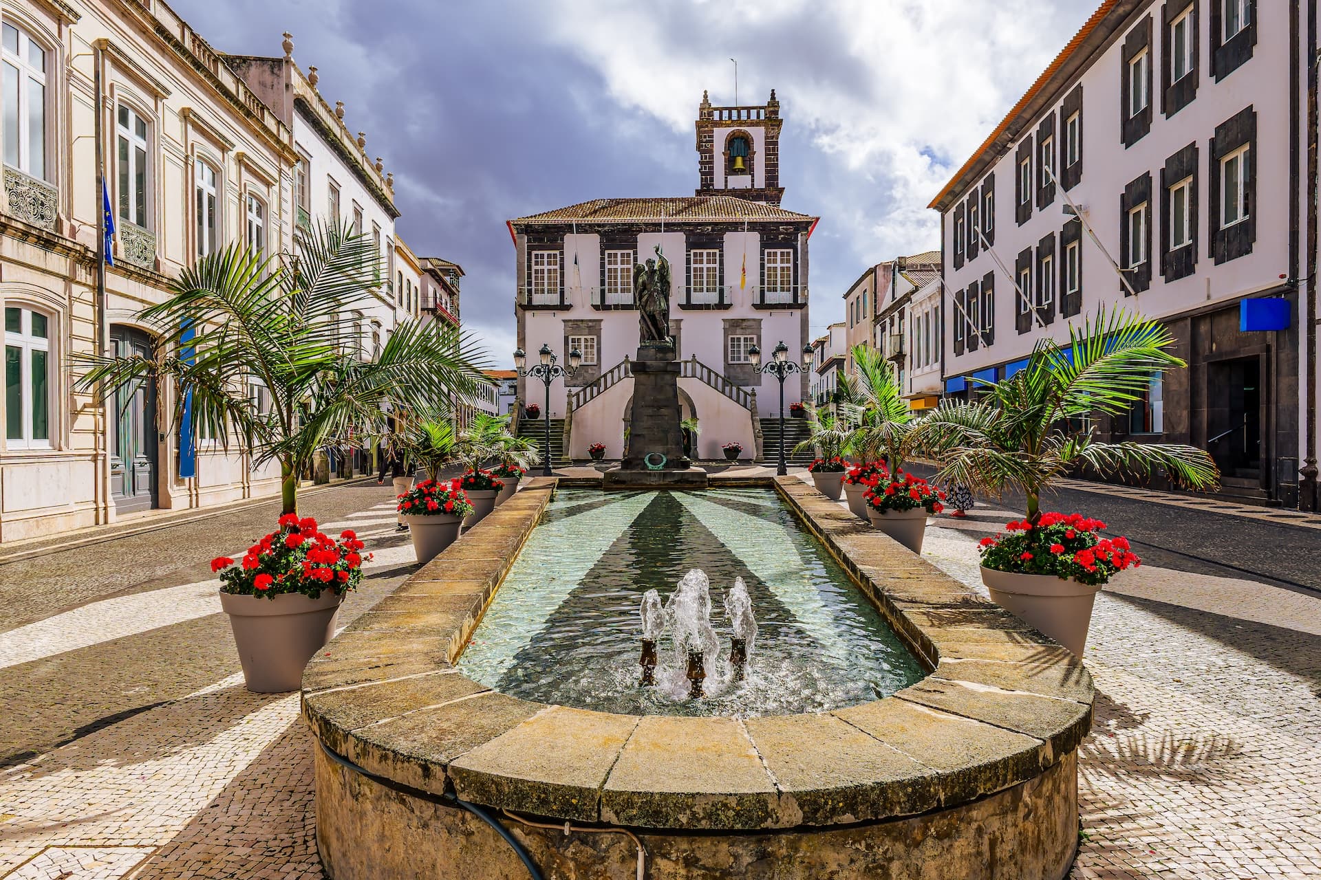 Fountain with jets in Town Hall Square, Ponta Delgada, with historic buildings.