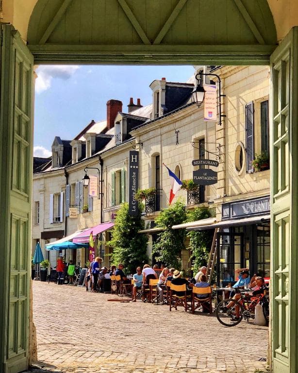 Outdoor cafe dining on a cobblestone street in a historic French town.