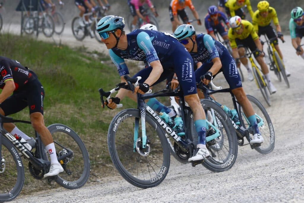 Professional cyclists racing on a gravel road in the Strade Bianche event.