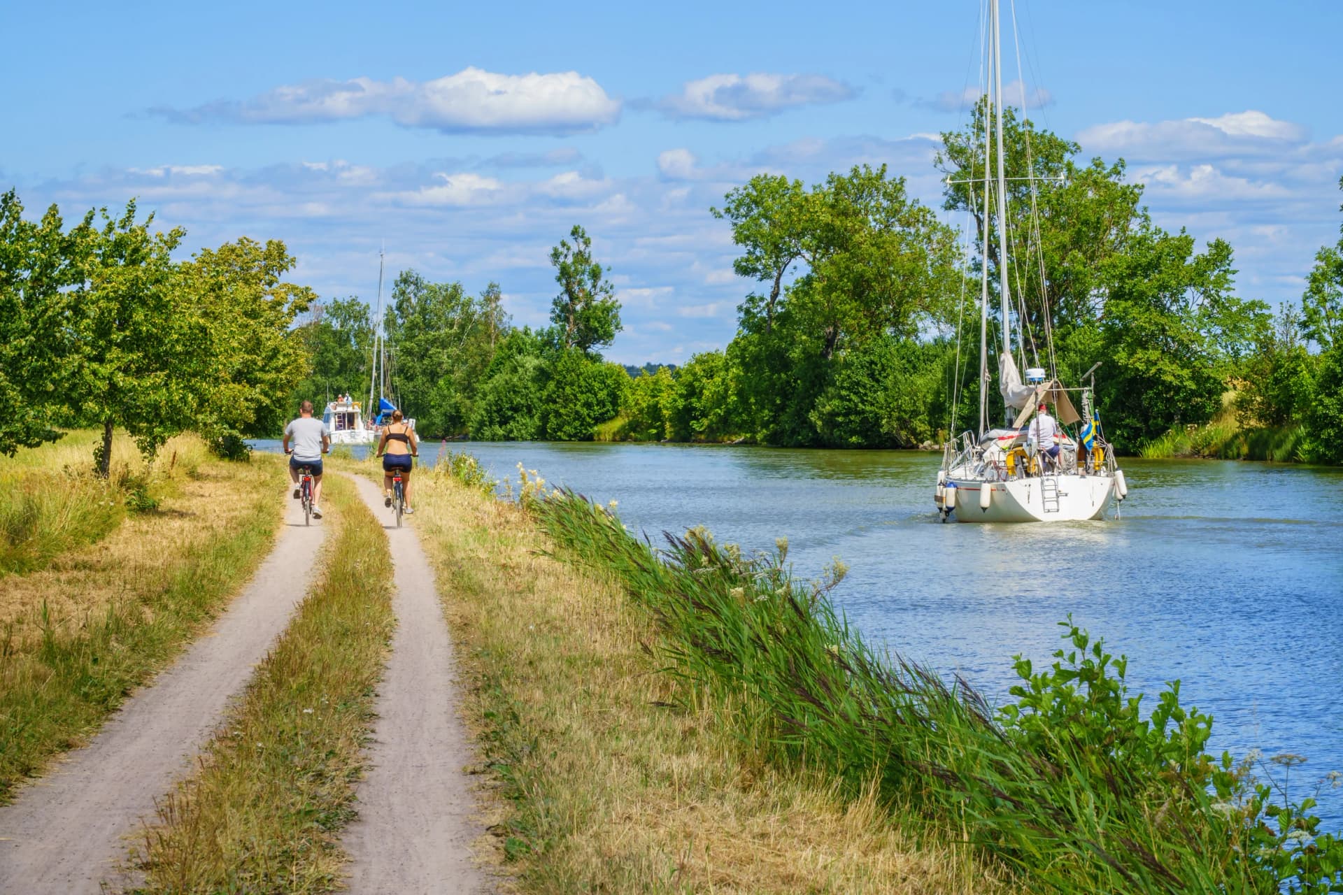 Couple cycling along a canal with boats